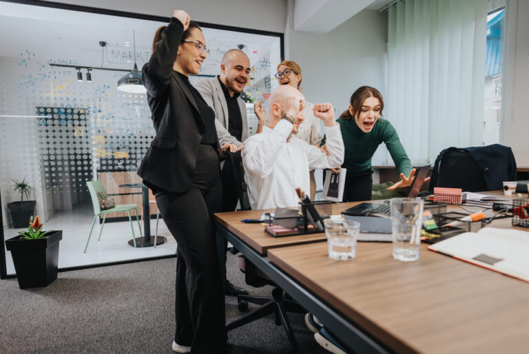Business leadership team celebrating during a strategic technology planning meeting in a modern office.