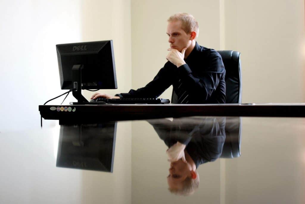 A business owner looks at his computer screen contemplatively as he thinks about cloud migration.