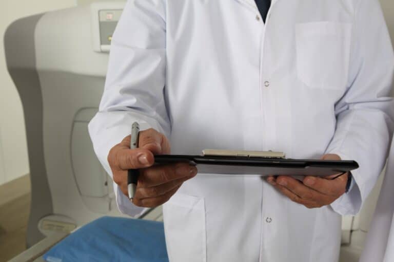 man in doctor lab coat holding tablet