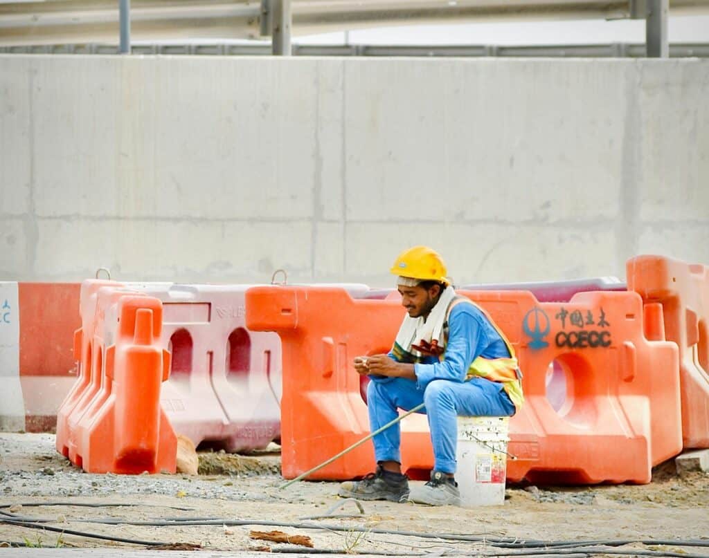 Construction worker in a hard hat checking a phone on site