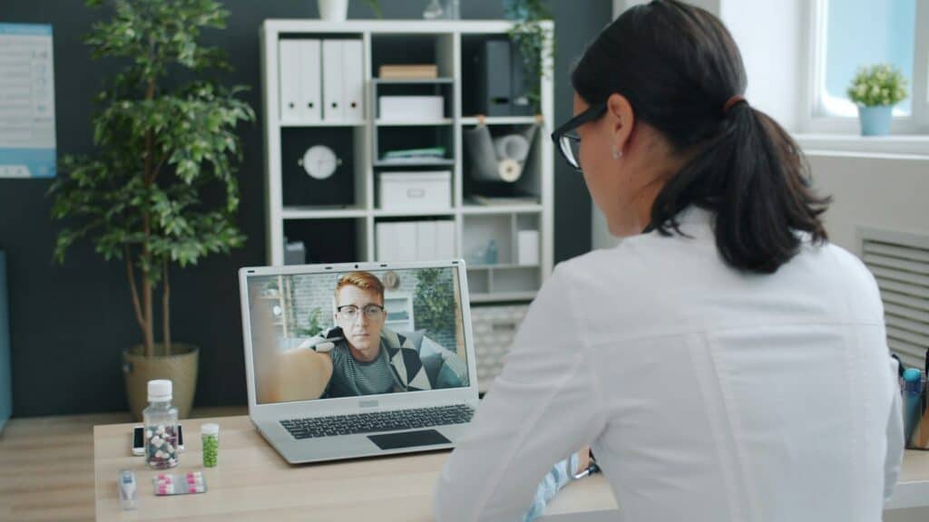 Doctor meeting with a patient through a telehealth video call on a laptop
