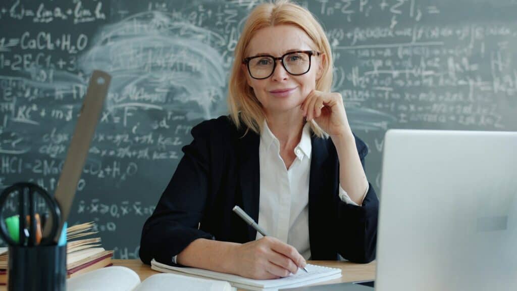 Teacher working on a laptop at a classroom desk