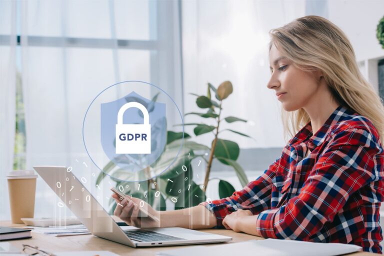Woman using a smartphone beside a laptop with a GDPR security icon overlay