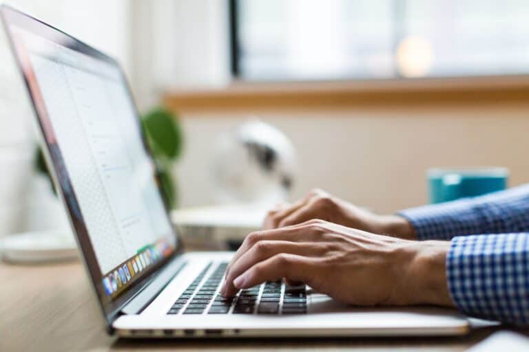 Stock image of hands typing at a laptop.