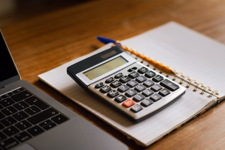 Accountant's desk with calculator, laptop and financial notes