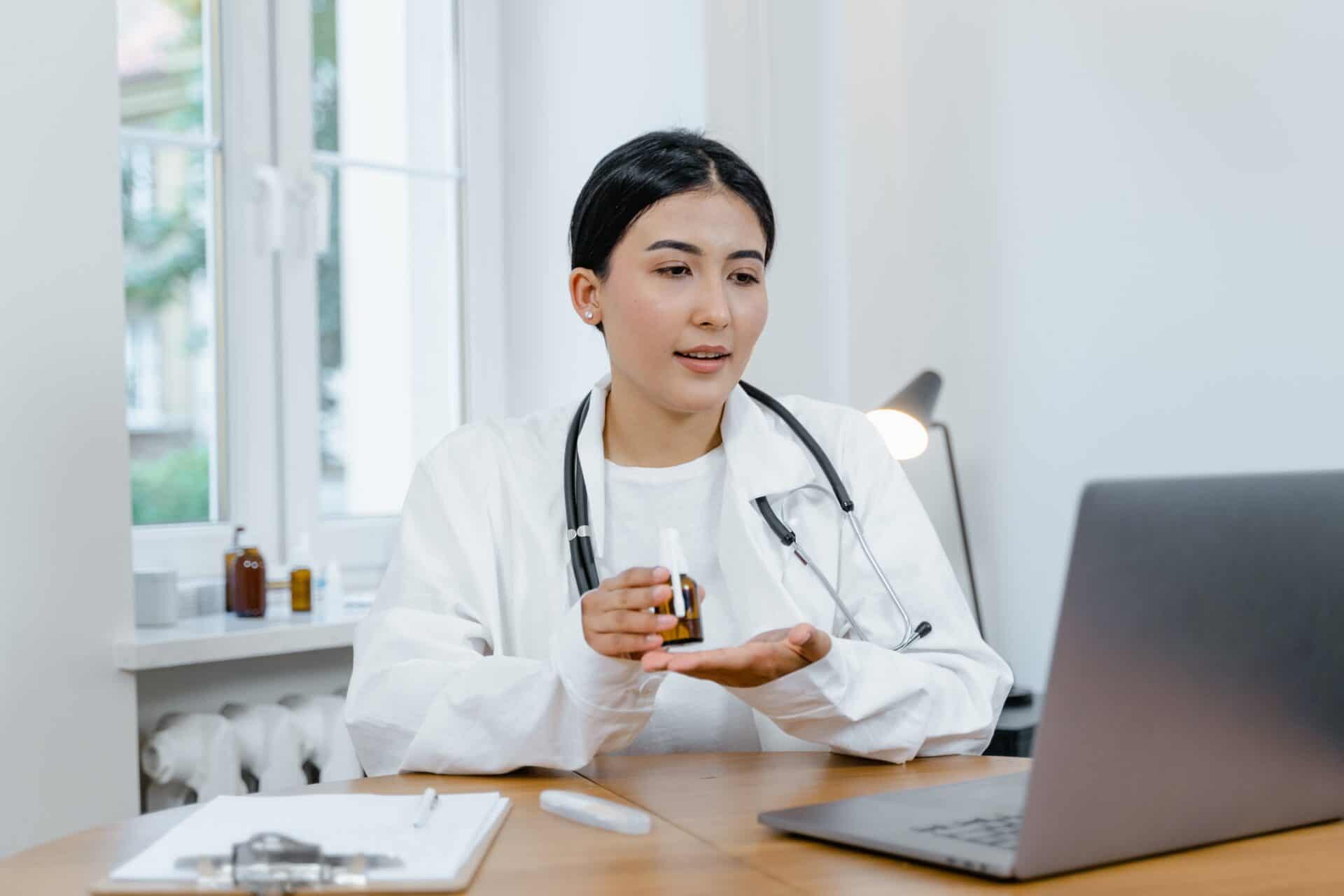 woman doctor in white coat looking at laptop