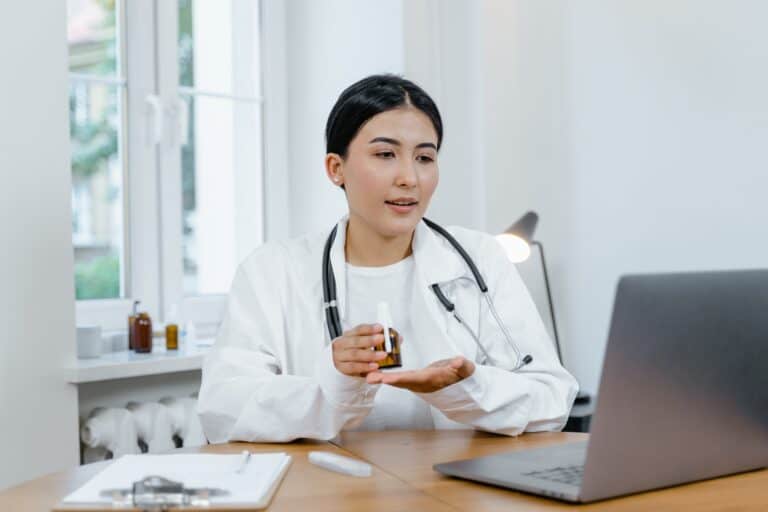 woman doctor in white coat looking at laptop