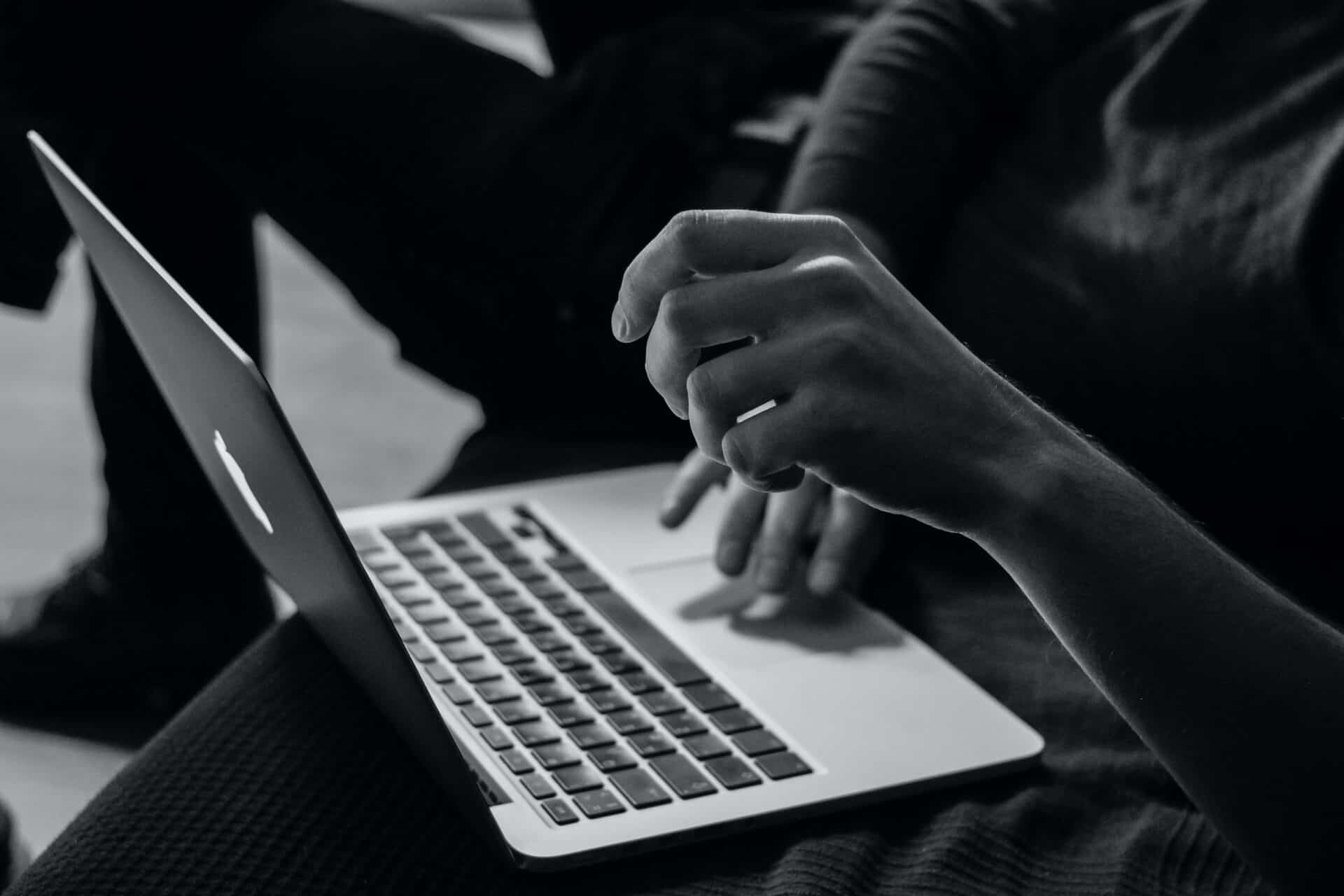 black and white photo of person typing at laptop