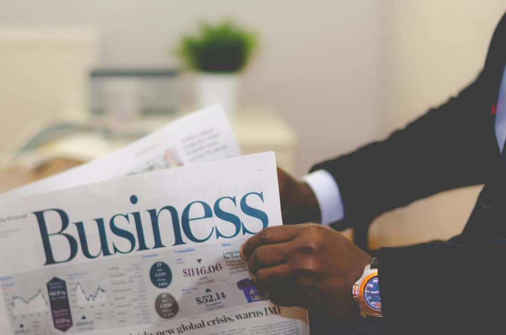 A closeup view of a suit-dressed business man's hands and arms holding and reading the business section of a newspaper