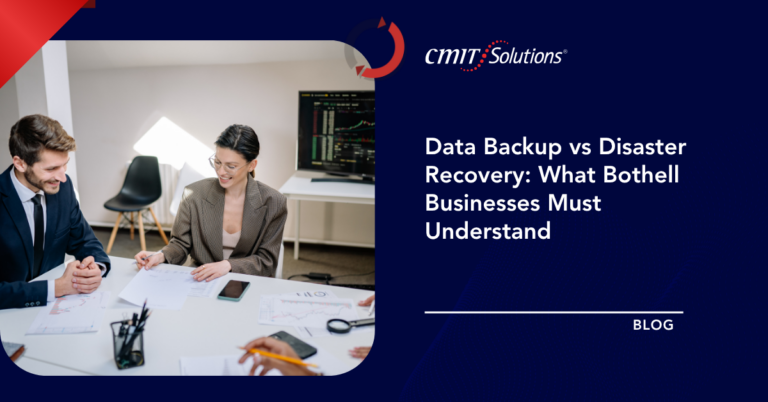 Two professionals at a white table review documents and charts in an office, for a blog on data backup vs disaster recovery.