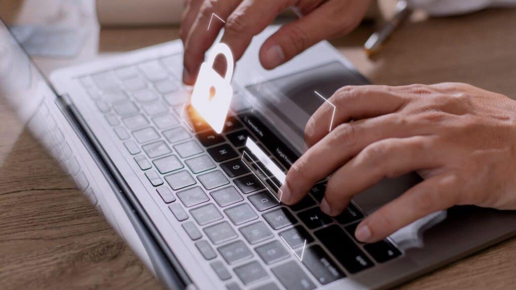 The image of a lock and login bars projects over a laptop keyboard with hands resting on it.