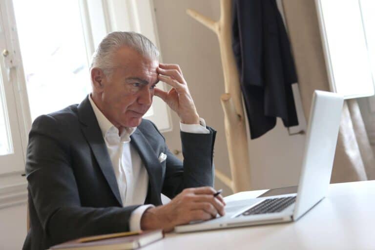 A businessman looks frustratedly at his computer after spotting a cyber attack.