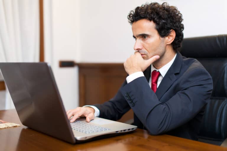 A man looks at his computer thoughtfully, trying to learn how to make his business more productive.