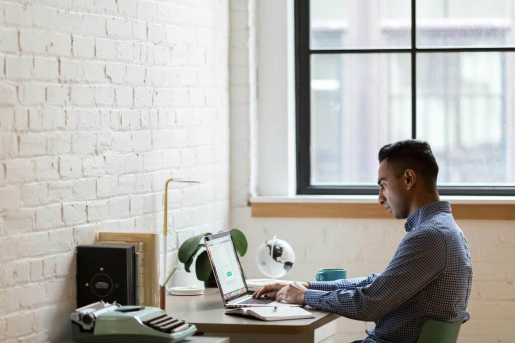 A male employee works on a laptop in an office.