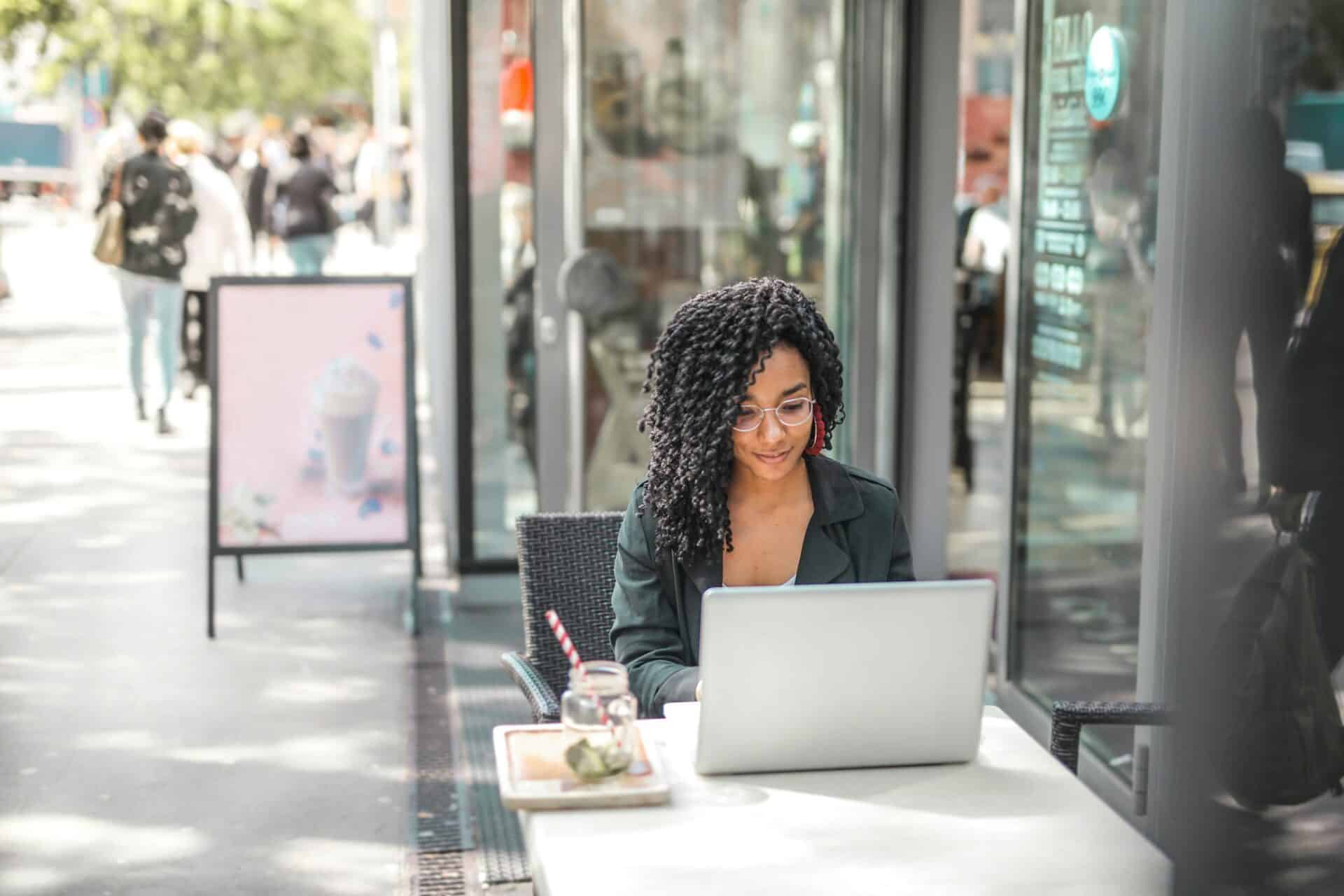 A female employee works at a cafe leveraging the power of cloud-based productivity apps.