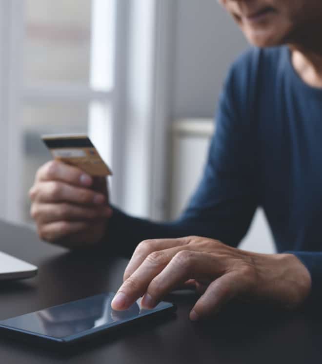 Man with a credit card using a tablet, illustrating online payment or checkout.