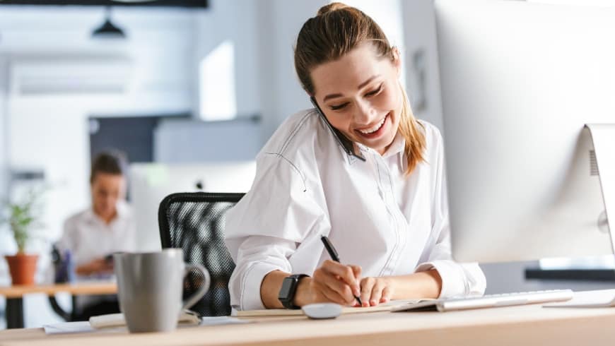 Smiling Woman Multitasking at Desk