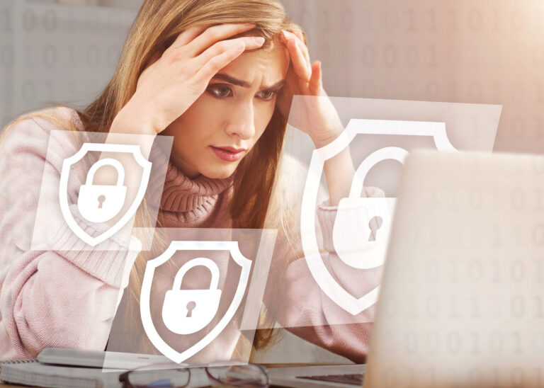 upset woman holds her head with hands and looks at laptop
