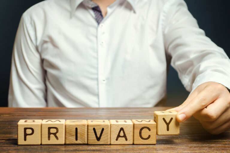 Person arranging wooden blocks spelling privacy