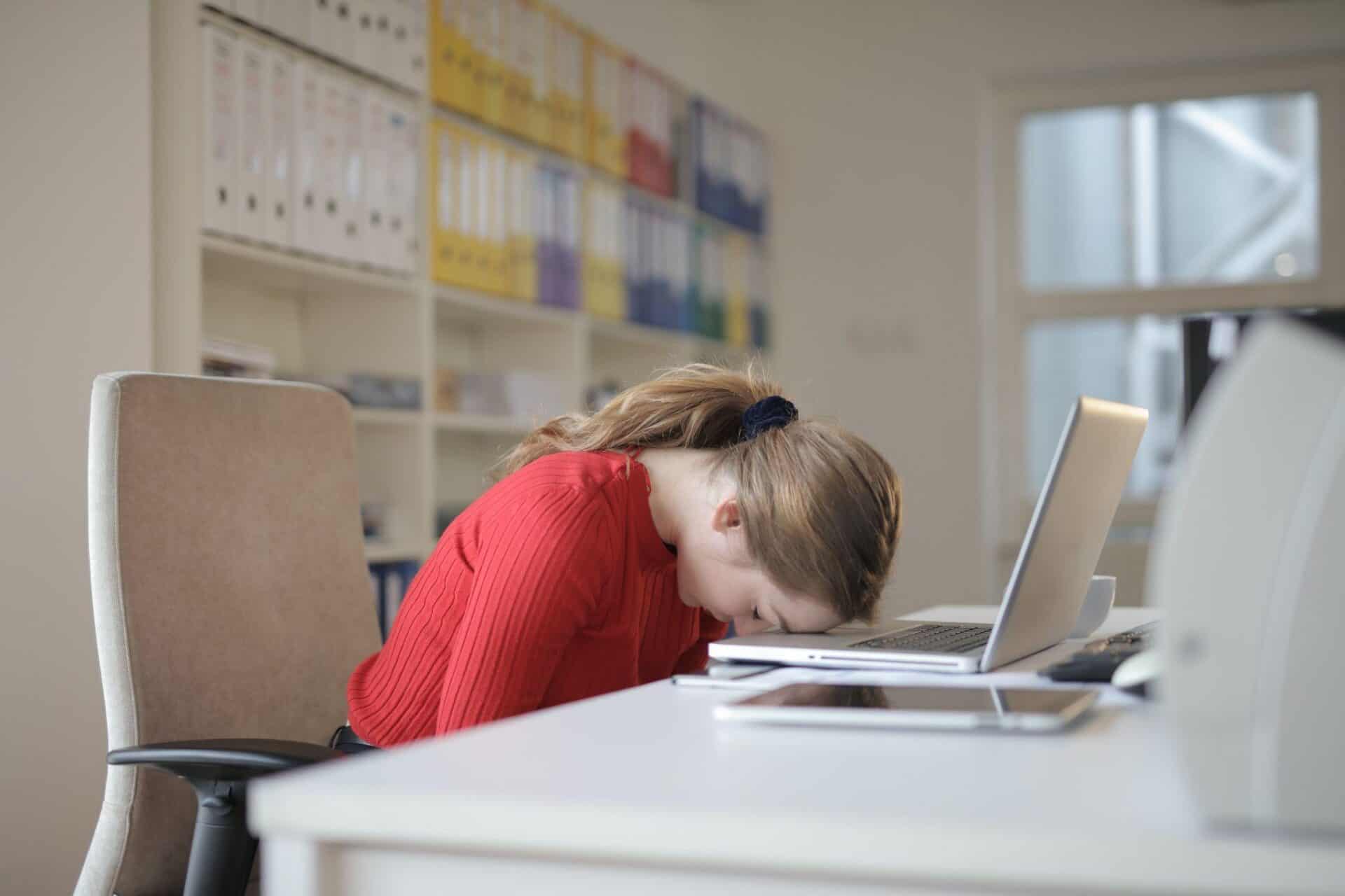 A business owner puts her head on her laptop keyboard as she realizes her business has been hacked