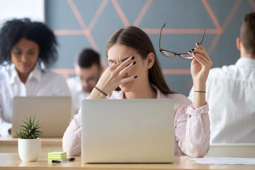 An employee reacts exasperatedly in front of her laptop as she falls for a cybersecurity threat.