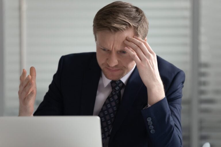 A business owner looks confusedly at his laptop, needing a disaster recovery plan.