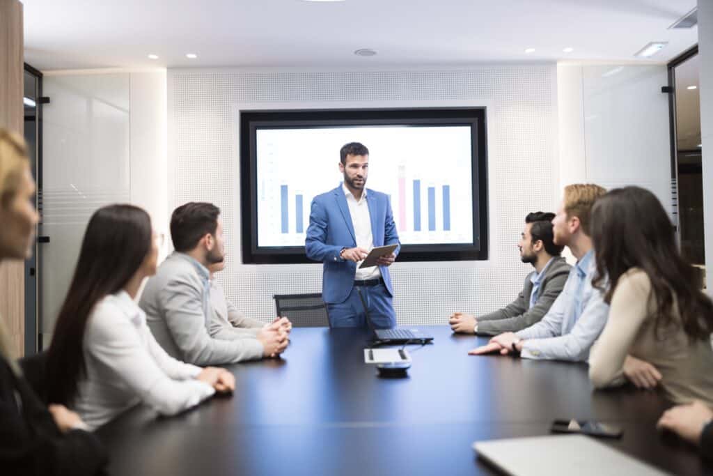 business owner leads an employee cybersecurity awareness training session for multiple employees.