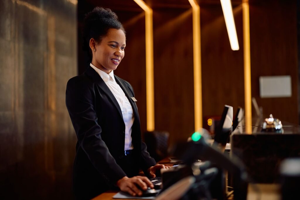 Black female concierge using computer while working at hotel front desk