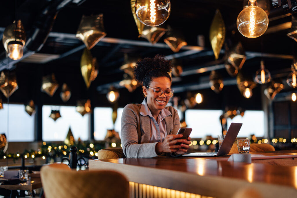 smiling-african-american-woman-reading-the-news-in- a-restaurant