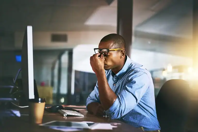 A frustrated managing partner in a blue shirt waiting on outdated systems in an office, illustrating the hidden cost of aging business technology.