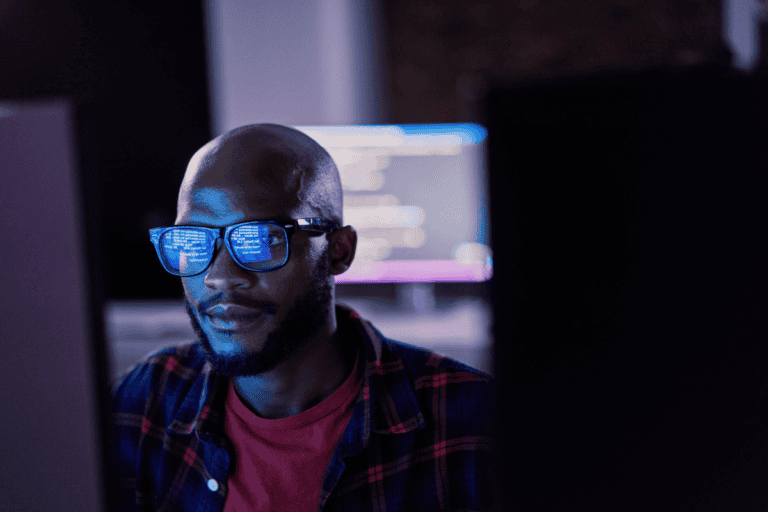 Cyber security, black man and code reflection in eyewear, hacking and software update in office. African American male employee, programmer or IT specialist with glasses, focus and cloud computing