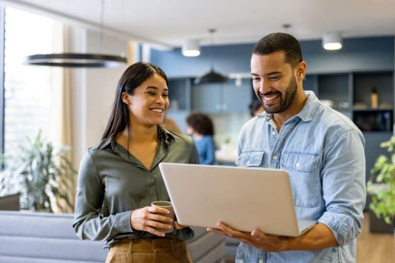 Two business professionals discussing cybersecurity strategies while reviewing information on a laptop in a modern office setting.