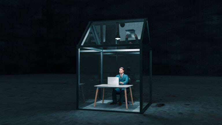 Man sits inside a small greenhouse and works on laptop. He is protected from outside threats. Concept of working securely from home.