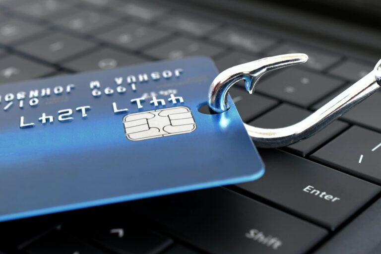 Blue credit card secured by a large metal lock on a laptop keyboard, symbolizing online security and fraud protection.