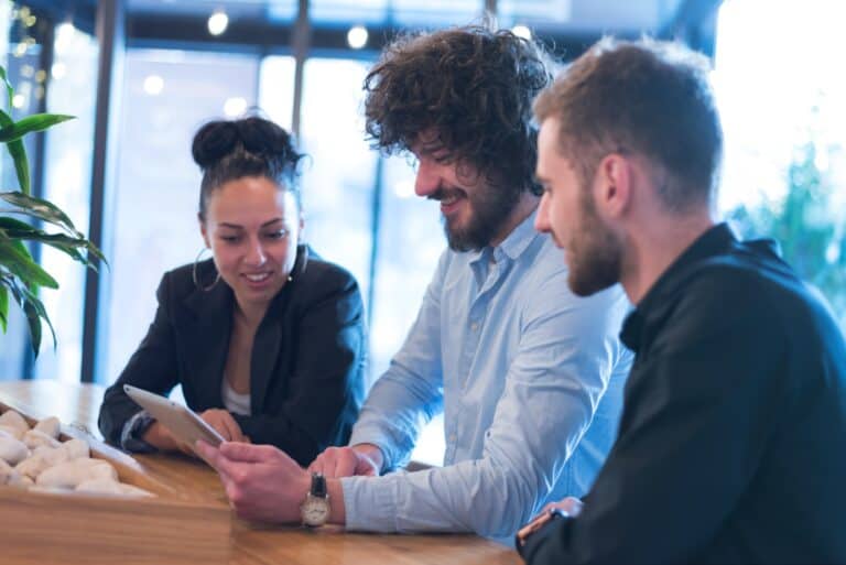 An employee shows two business owners a new data backup and disaster recovery plan on his tablet.