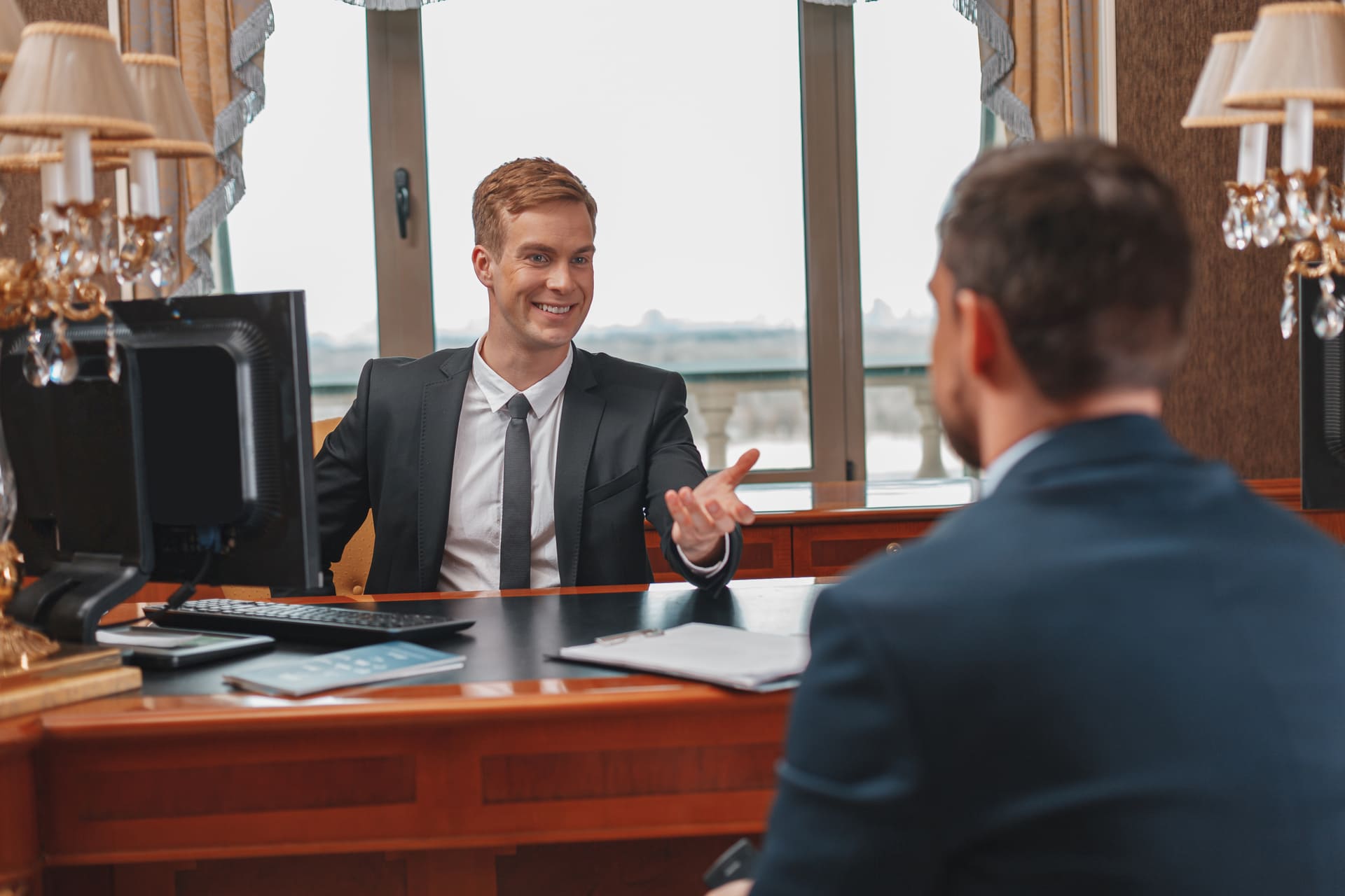 smiling-hotel-receptionist-helping-businessman