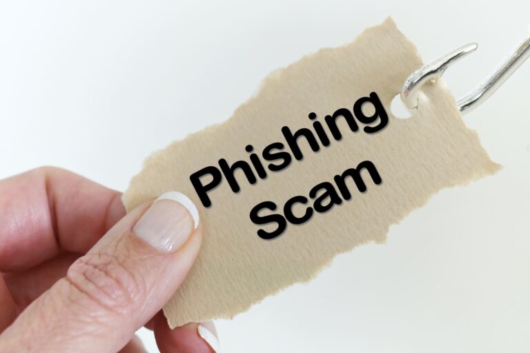 fingers hold paper with phising scam words on it