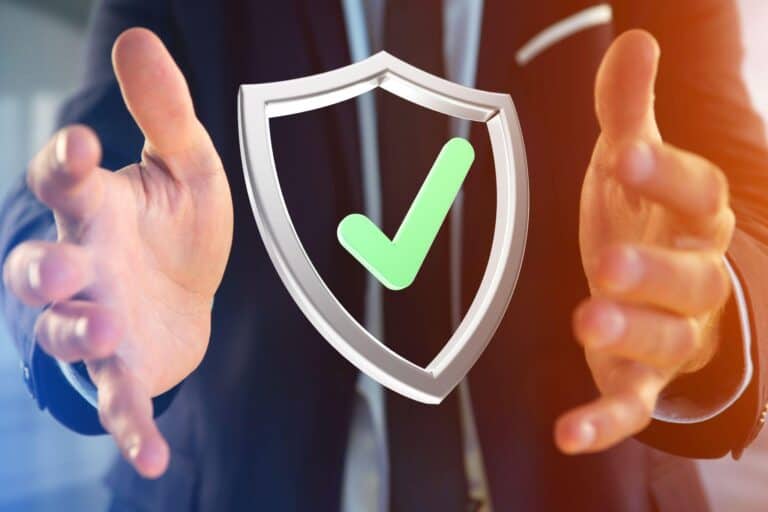 A businessman reaches to grab the image of a shield and a green checkmark depicting IT security.