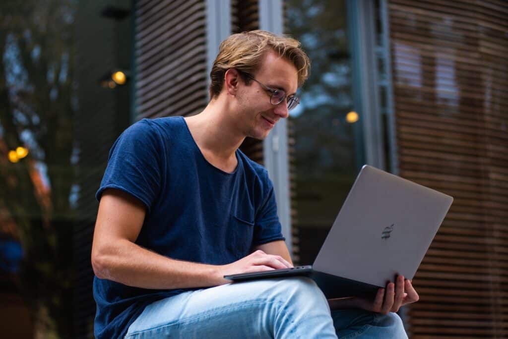 A college student works on his laptop happily as his private details are safe under compliance.