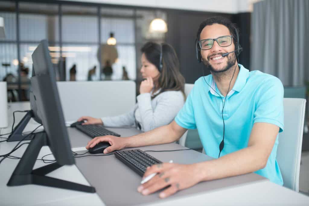 Two employees go through cybersecurity awareness training while one smiles at the camera. Two employees go through cybersecurity awareness training while one smiles at the camera.