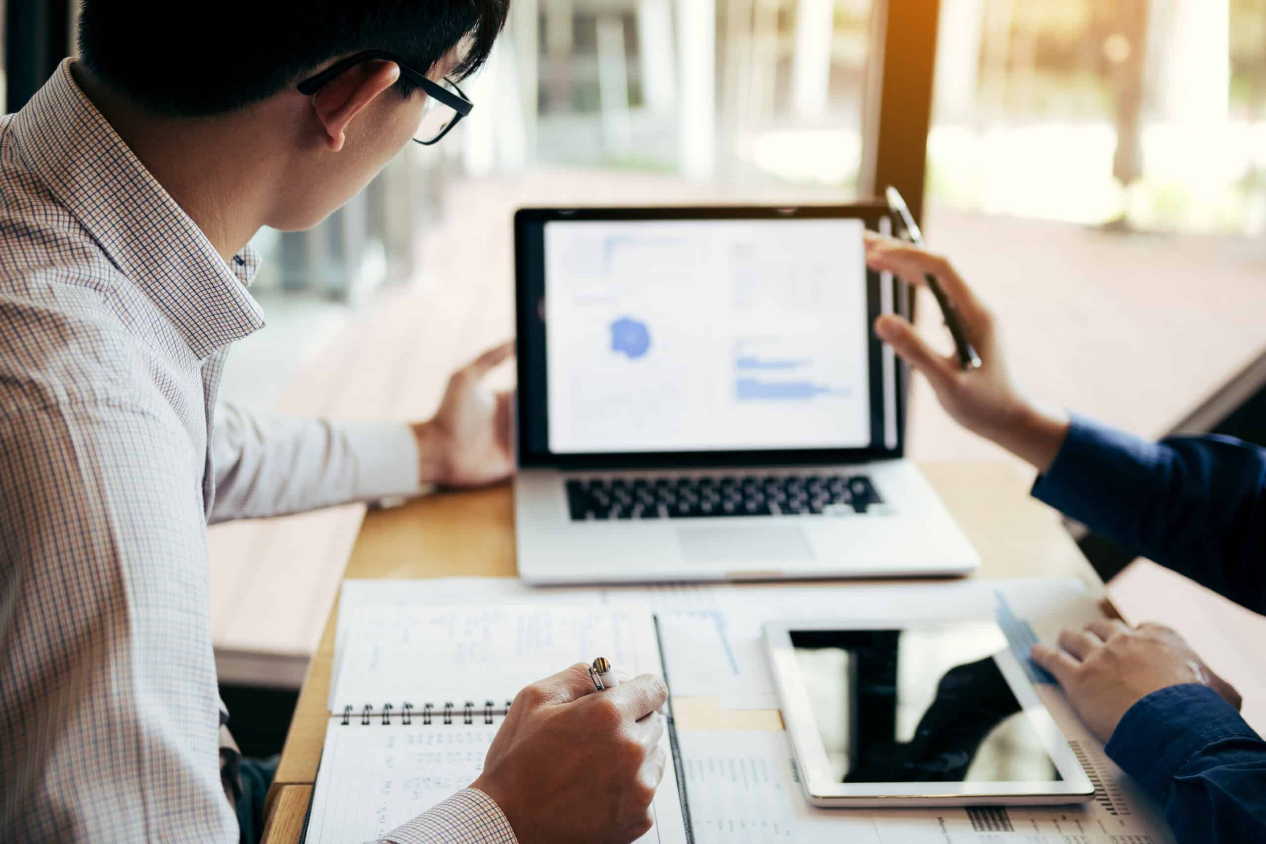 A person explaining IT strategies to another person using his laptop.