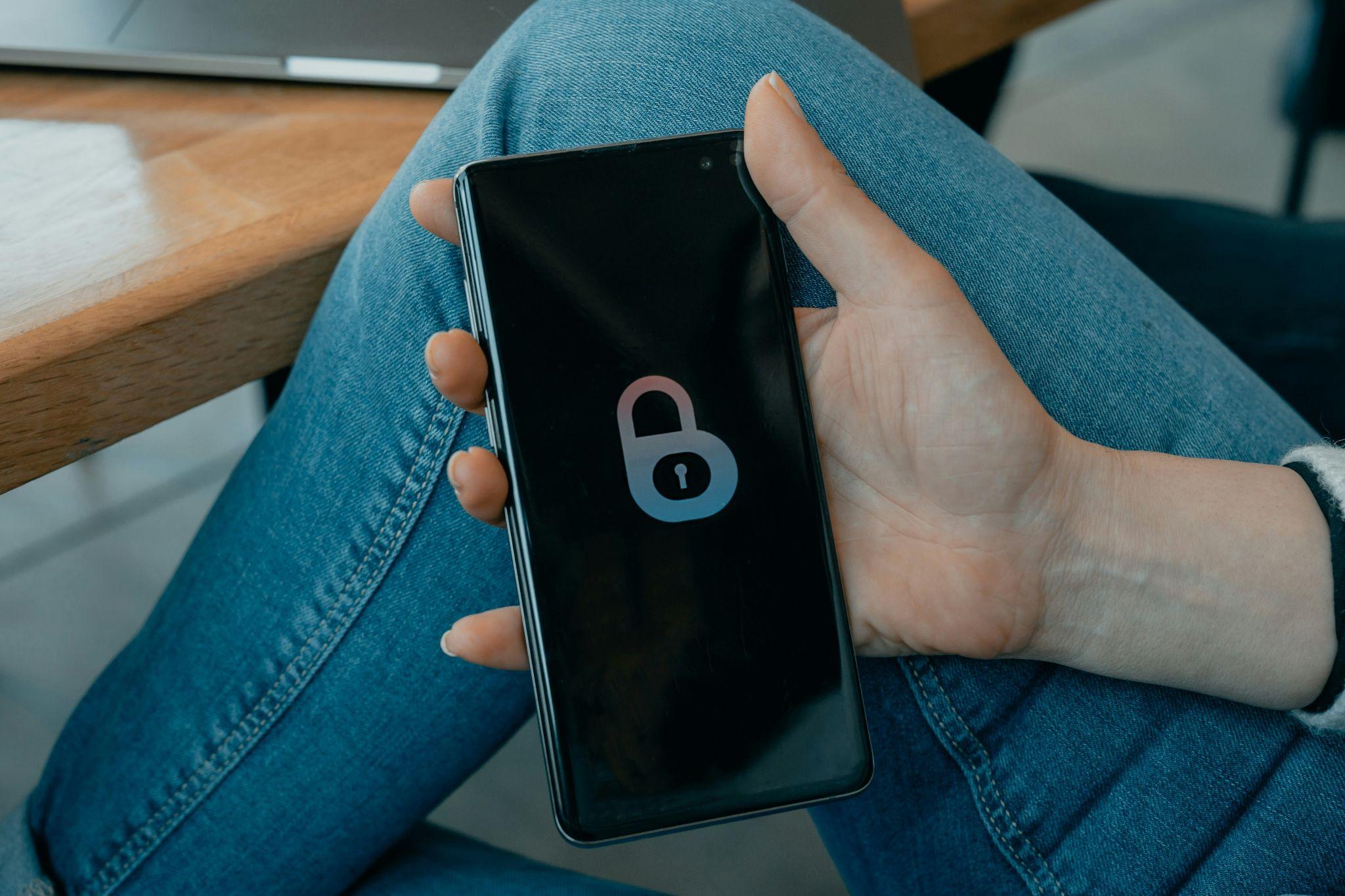 A person’s hand holding a smartphone with an image of a lock on the screen
