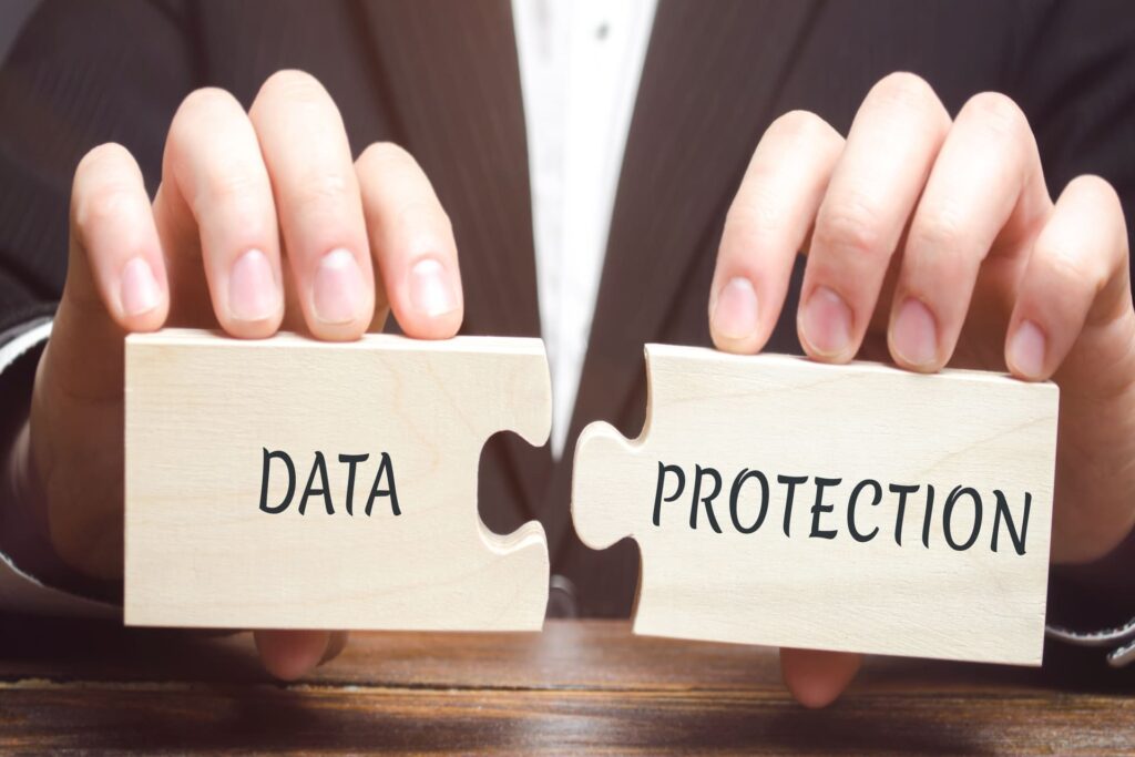 Businessman holding wooden puzzle pieces labeled data protection