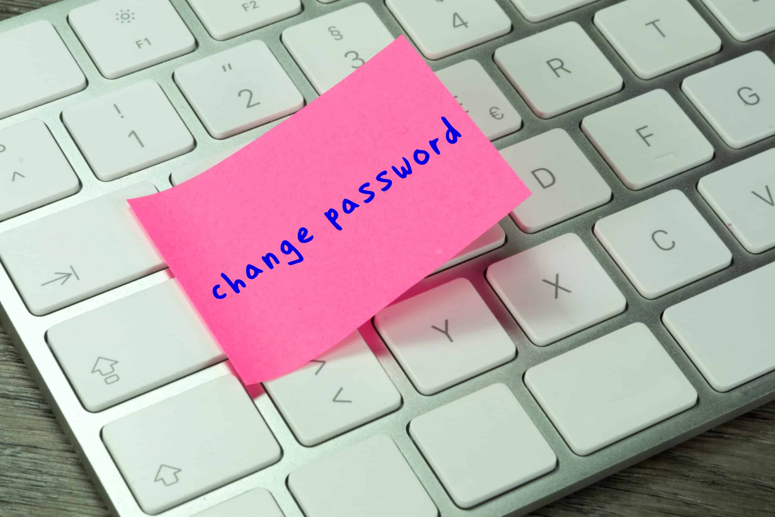 A pink sticky note on a keyboard with white keys reminds a business owner to change their password.
