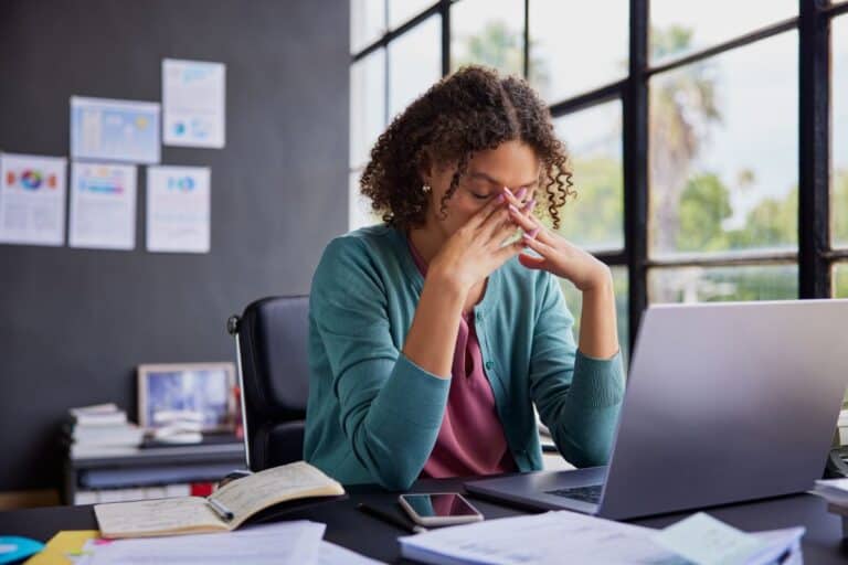 Stressed professional at a computer, representing the impact of emerging cybersecurity threats businesses face in 2025