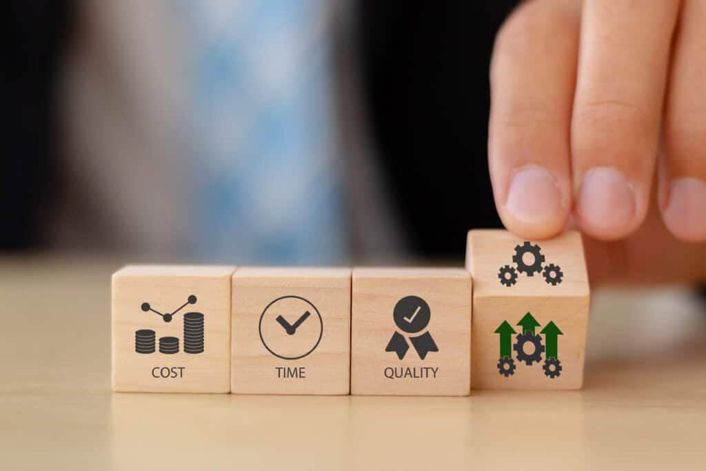 A hand moving one wooden block of four that have prints on them including a graph chart, checkbox, ribbon award and mechanical gears.