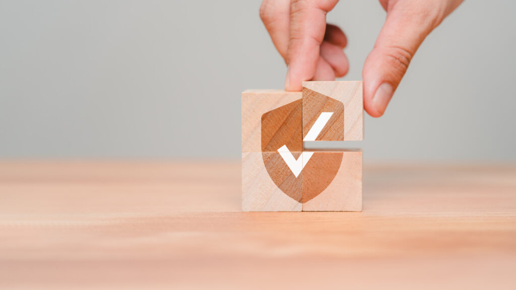 Hand put a wooden cube block with identity proof icon for security protection system on wood table. Quality assurance of business service. Certified guarantee approval or secure access system concept.