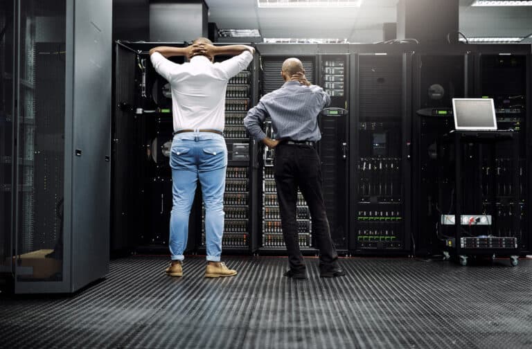 Rearview shot of two IT technicians having difficulty repairing a computer in a server room