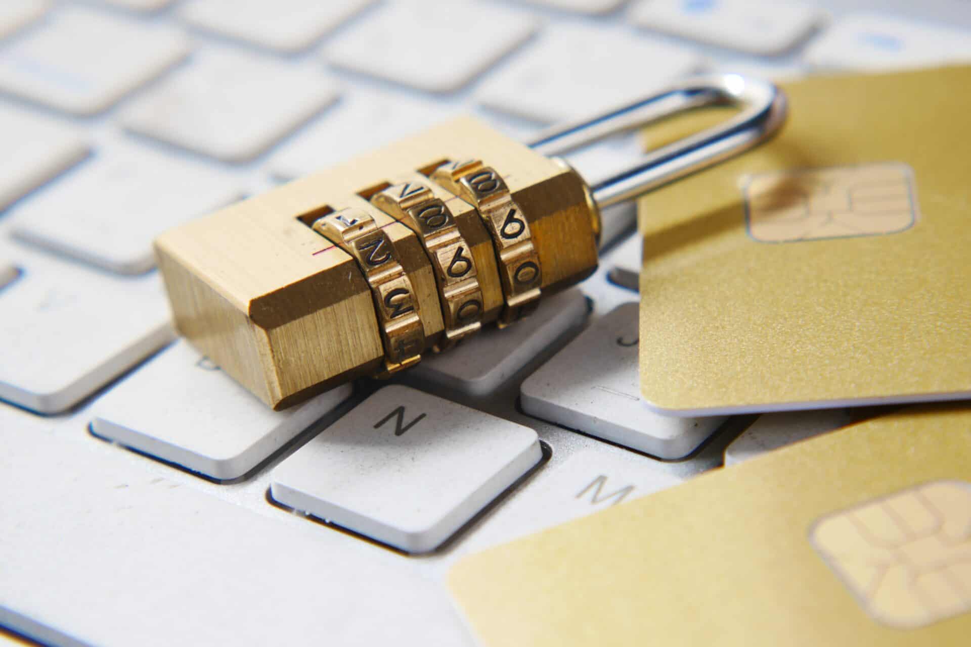 :A combination lock with three dials and some chip-embedded cards sits on top of a white keyboard.