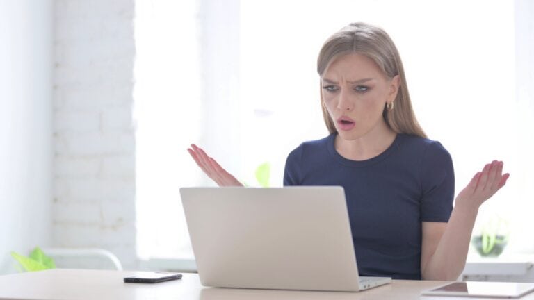 A business owner throws up her hands as she sees a cybersecurity attack on her computer.